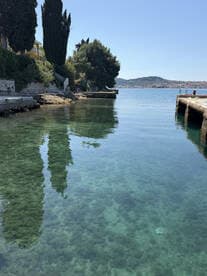 A serene view of a clear water inlet with reflections of trees and a distant shoreline, ideal for capturing the tranquility of coastal landscapes.