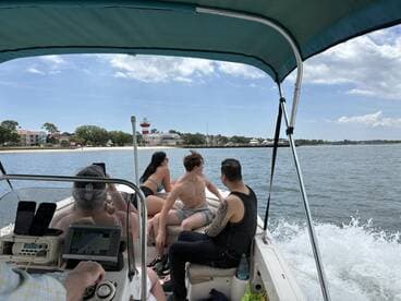 A group of friends enjoys a scenic boat ride, capturing moments with a lighthouse in the background — perfect for summer adventures on the water.