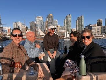 A cheerful group enjoys a boat ride with a stunning cityscape backdrop, perfect for social gatherings and celebrations on the water.