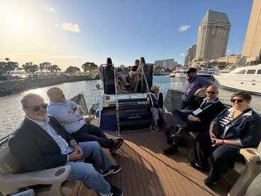 A group of guests enjoy a scenic boat ride, surrounded by the vibrant city skyline and waterfront views, perfect for social gatherings or corporate events.