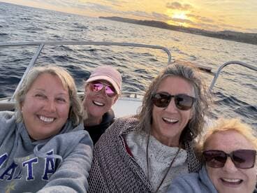 A group of friends enjoys a joyful moment on a boat at sunset, capturing the essence of friendship and celebration on the water.