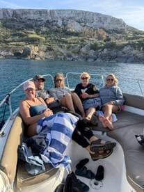 A group of friends relaxes on the deck of a boat, enjoying the beautiful scenery and each other's company — perfect for a day out on the water.
