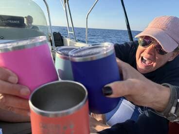 A lively group cheers with colorful drink tumblers aboard a boat, capturing the essence of fun and celebration on the water.
