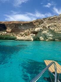 A stunning view of a rocky coastline with crystal-clear turquoise waters, perfect for exploring by boat or enjoying a scenic cruise.