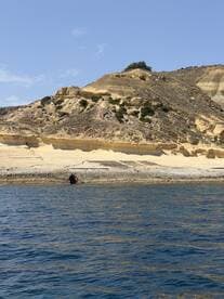 A stunning view of a rugged coastline with unique rock formations, perfect for showcasing the natural beauty of the area during a boating trip.