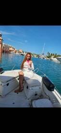 A woman enjoys a refreshing cocktail aboard a boat, basking in the sunny atmosphere — perfect for a day of relaxation on the water.
