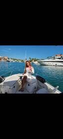 A woman enjoys a cocktail on the deck of a boat, surrounded by beautiful waterfront scenery — perfect for a relaxing day on the water.