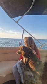 A girl enjoys a serene moment on a boat with her dog, taking in the beautiful water views — a perfect snapshot of companionship on the water.