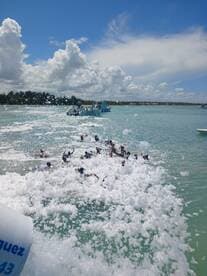 A lively group enjoys a fun day in the water, splashing through foam and waves, creating unforgettable memories on a beach adventure.
