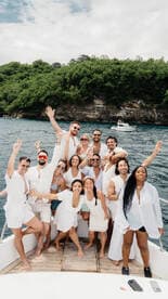 A lively group of friends celebrates together on a boat, showcasing joy and camaraderie against a beautiful natural backdrop.
