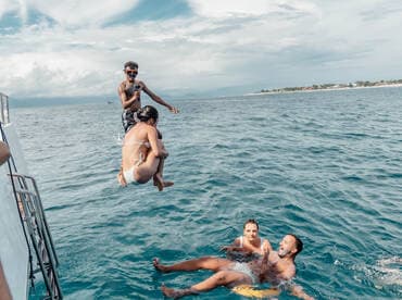 A thrilling moment captured as a group enjoys jumping off the boat into the ocean, showcasing the fun and excitement of a day on the water.