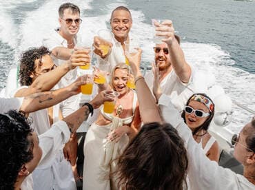 A lively group toasts with cocktails aboard a boat, celebrating together under the sun — perfect for memorable gatherings and parties on the water.