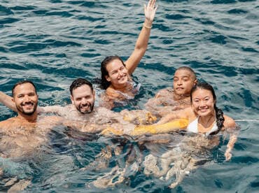 A joyful group of friends enjoys a refreshing swim in the ocean, capturing the essence of fun and adventure on their boating trip.