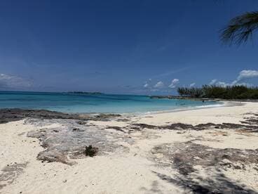A picturesque beach scene featuring turquoise waters and soft sand, with a group of people enjoying the sun and surf — a perfect tropical getaway.