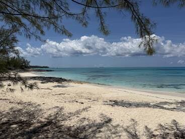 A serene view of a pristine beach with turquoise waters and a clear sky, perfect for relaxation and enjoying nature's beauty.