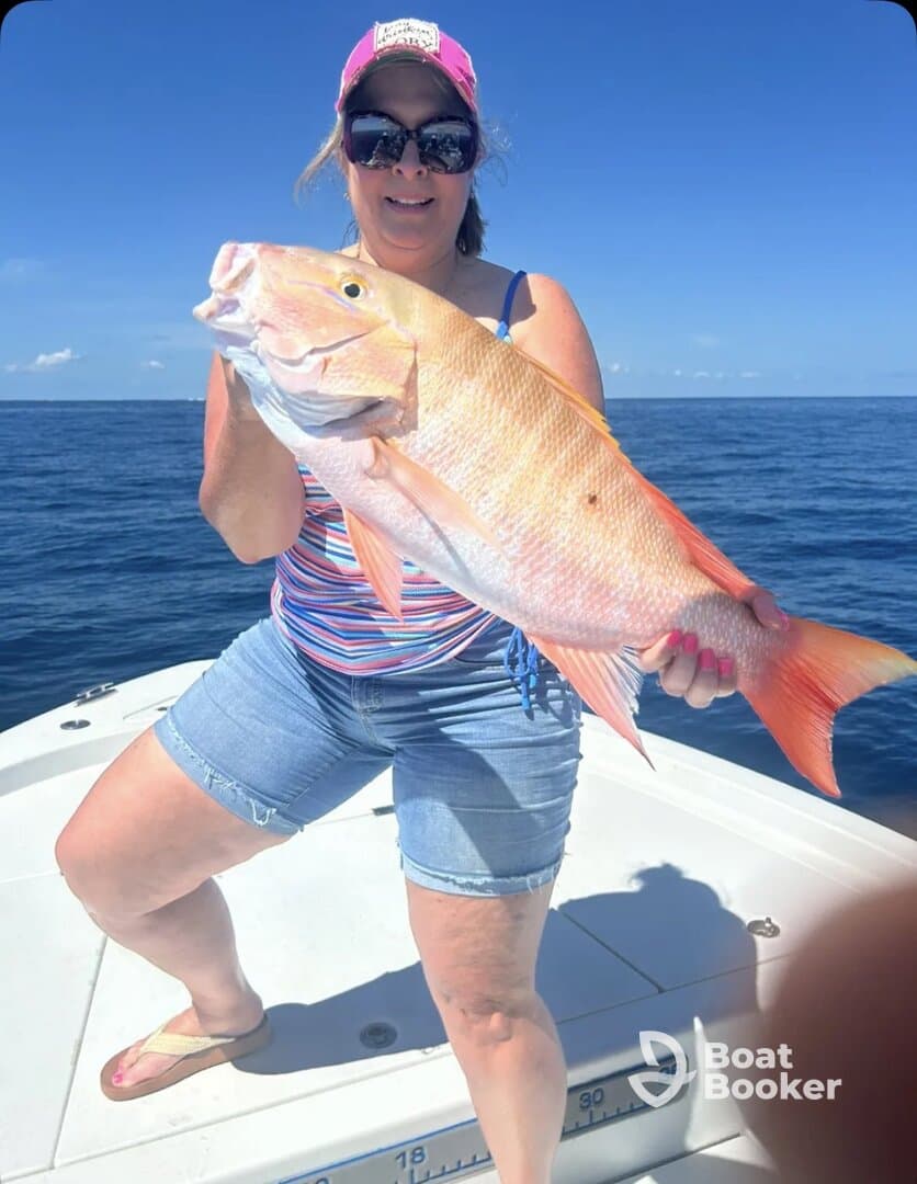 A woman proudly displays her impressive catch while fishing on a boat, showcasing the thrill of a successful day on the water.