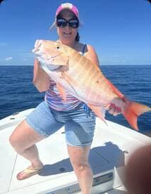 A woman proudly displays her impressive catch while fishing on a boat, showcasing the thrill of a successful day on the water.