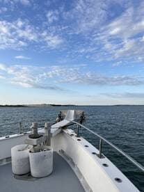 A serene view from the bow of a boat, showcasing the vessel's structure against a backdrop of calm waters and a clear sky, perfect for a peaceful day on the water.