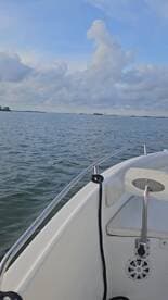 A serene view from the bow of a boat, showcasing calm waters and a cloudy sky — perfect for a peaceful day on the water.