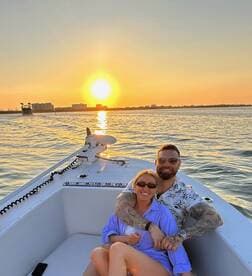 A couple enjoys a romantic sunset cruise on a boat, celebrating with drinks as the sun sets over the water — an ideal moment for love and connection.