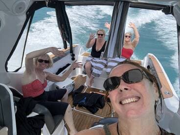 A joyful group of friends enjoys a fun day on the water, capturing memories aboard a boat with smiles and waves.