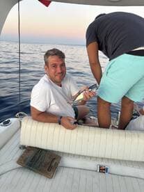 A man proudly displays his catch while fishing on a boat, showcasing the excitement of a day on the water with friends.