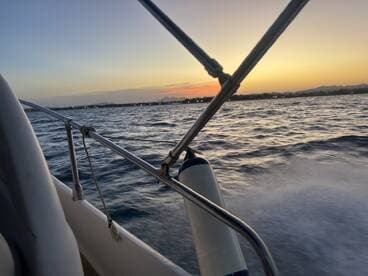 A serene view of a boat in motion during sunset, showcasing the tranquil waters and distant shoreline — perfect for evening cruises.