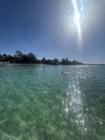 Two swimmers enjoy the crystal-clear waters on a sunny day, showcasing the perfect beach experience.
