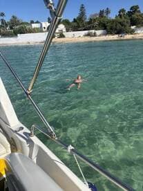 A person enjoys a refreshing swim in the clear waters near a beach, showcasing the perfect setting for a relaxing day on the water.
