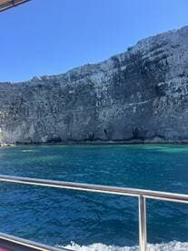 A stunning view of a rocky coastline from a boat, showcasing the vibrant blue waters and dramatic cliffs — perfect for scenic boat tours.