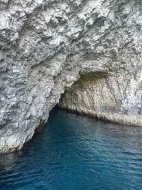 A stunning view of a coastal cave with crystal-clear waters, perfect for exploring hidden gems during a boat trip.