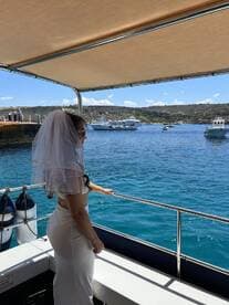 A bride gazes out at the ocean from a boat, capturing a beautiful moment during her wedding celebration — perfect for romantic maritime adventures.