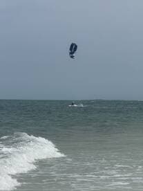 A thrilling kitesurfer rides the waves, showcasing the excitement of water sports in a beautiful coastal setting.