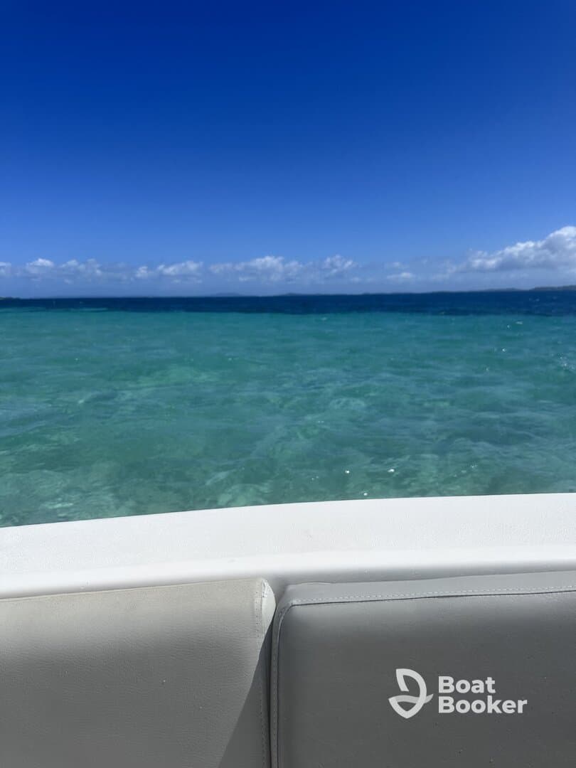 A serene view from the edge of a boat, showcasing the stunning turquoise waters and clear blue skies — perfect for a relaxing day on the water.