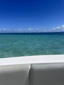 A serene view from the edge of a boat, showcasing the stunning turquoise waters and clear blue skies — perfect for a relaxing day on the water.