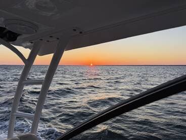 A serene sunset view from the deck of a boat, showcasing the tranquil waters and vibrant colors of the evening sky — perfect for romantic cruises or peaceful getaways.