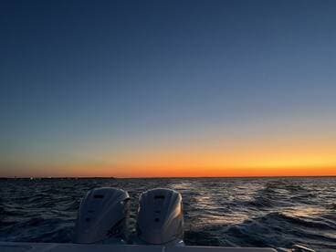 A serene sunset view from the back of a boat, showcasing the tranquil waters and vibrant sky — perfect for evening cruises.