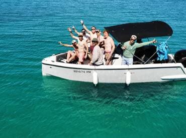 A lively group of friends celebrates aboard a boat in crystal-clear waters, capturing the essence of fun and adventure on the water.