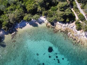Aerial view of a serene beach with clear turquoise waters and lush greenery, showcasing a perfect coastal getaway.