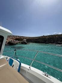 A scenic view from the deck of a boat, showcasing clear turquoise waters and rocky cliffs in the background — perfect for exploring coastal destinations.