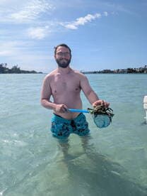 A man enjoys a day in the water, proudly holding a crab caught with a net — a perfect snapshot of outdoor adventure and fishing fun.