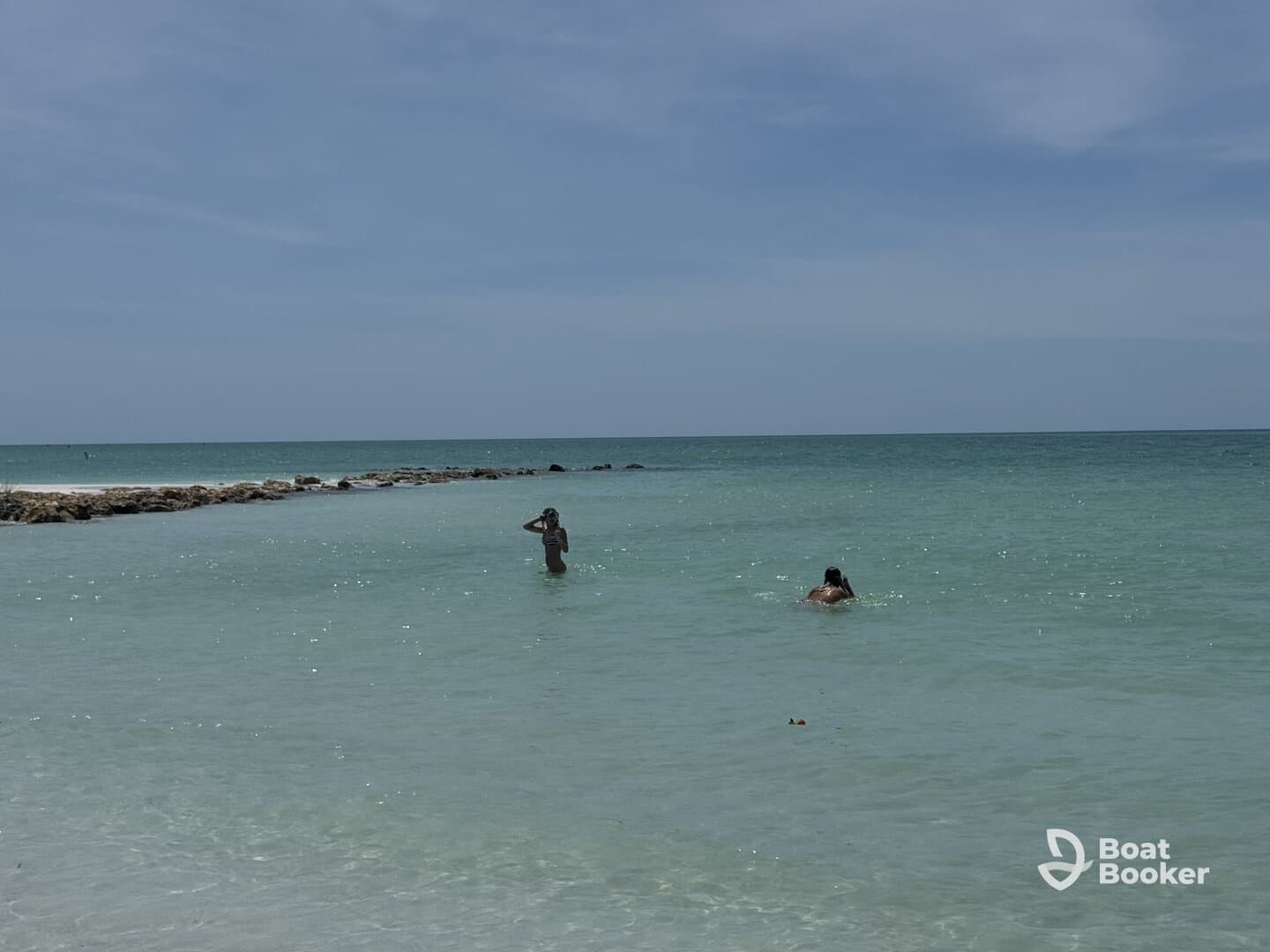 Two individuals enjoy a refreshing swim in the clear waters, capturing the essence of a perfect beach day.