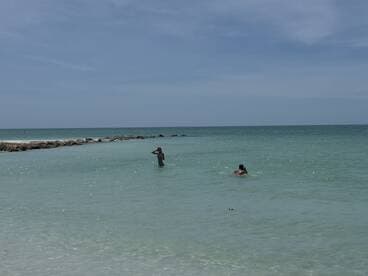 Two individuals enjoy a refreshing swim in the clear waters, capturing the essence of a perfect beach day.