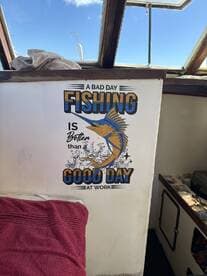 A cozy interior of a fishing boat featuring a humorous sign that reads, 'A bad day fishing is better than a good day at work.' Perfect for fishing enthusiasts looking to relax on the water.