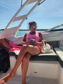 A woman relaxes on the plush seating of a boat, enjoying the sunny day on the water — perfect for leisure and relaxation.