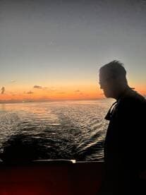 A silhouette of a person against a stunning sunset backdrop, capturing the serene beauty of a boat ride at dusk.