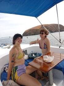 Two friends enjoy a fun moment on a boat, showcasing their joy and camaraderie against a scenic backdrop — perfect for memorable outings on the water.