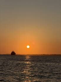 A serene sunset view featuring a boat silhouetted against the vibrant orange sky, creating a picturesque scene on the water.