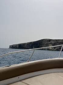A scenic view from the deck of a boat, showcasing a rugged coastline against the backdrop of calm waters — perfect for exploring coastal destinations.