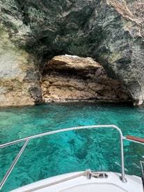 A stunning view of a natural rock arch over turquoise waters, showcasing the beautiful coastline — perfect for exploring hidden gems while boating.